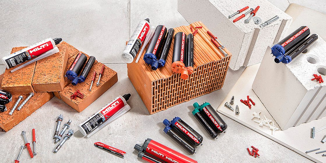 verschiedene Hilti Dübel liegen verteilt auf verschiedenen Untergründen wie Vollstein, Lochstein und Porenbeton