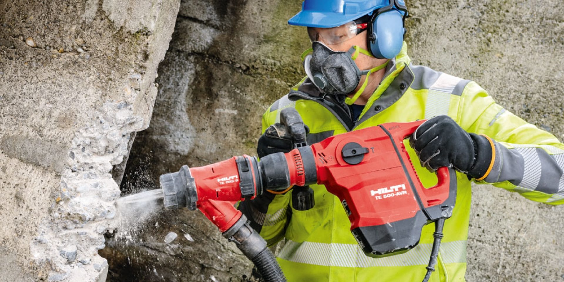 Ein Bild eines Arbeiters, der auf der Baustelle mit einem Hilti Meißelhammer TE 500-AVR mit TE DRS Staubabsorptionsmodul an der Betonwand arbeitet.