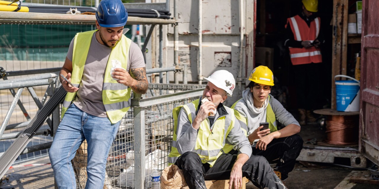 Aufnahme von drei Bauarbeitern, die auf einer Baustelle Pause machen. 