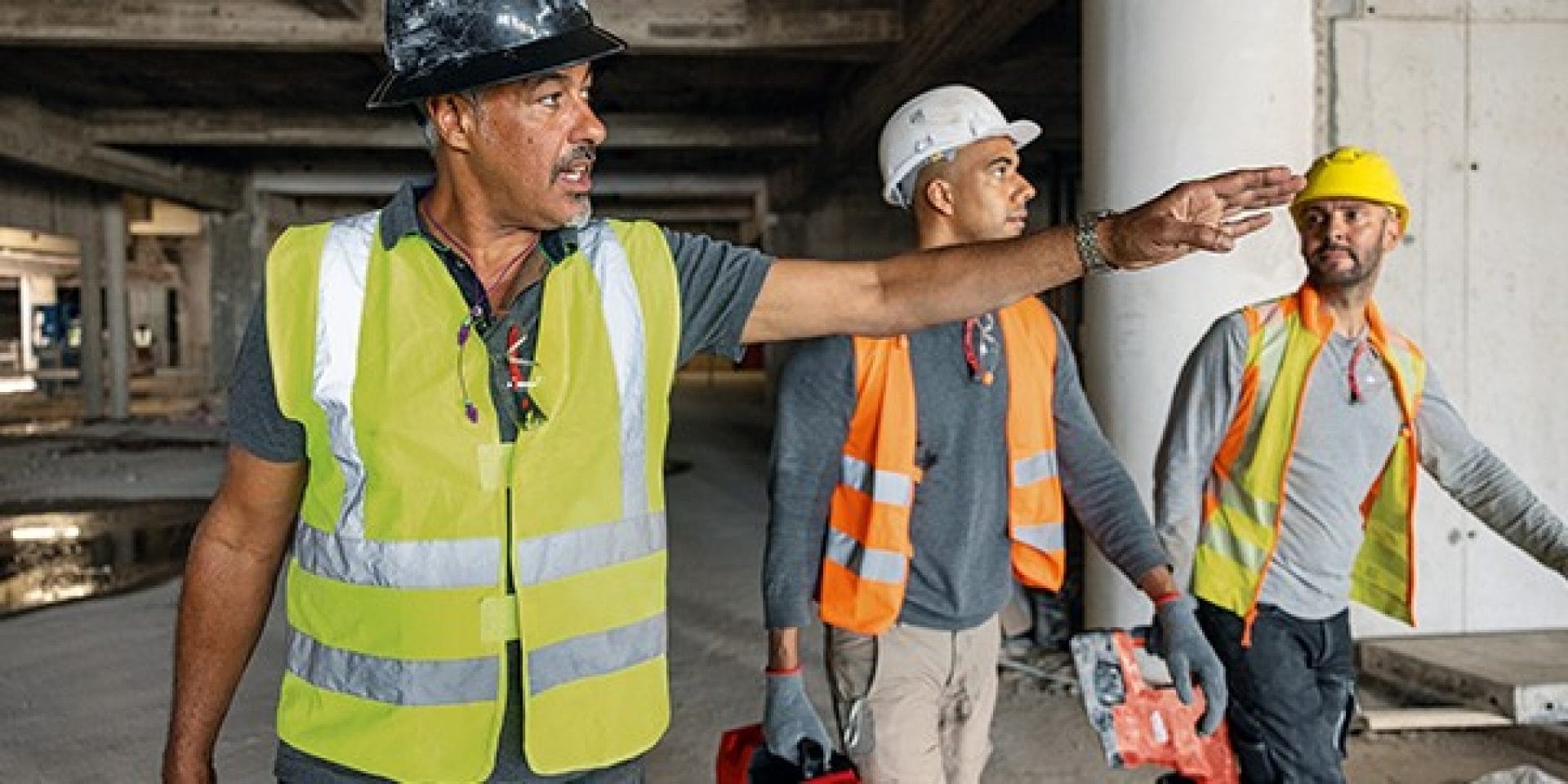 Bauleiter zeigt 2 Arbeitern den Weg