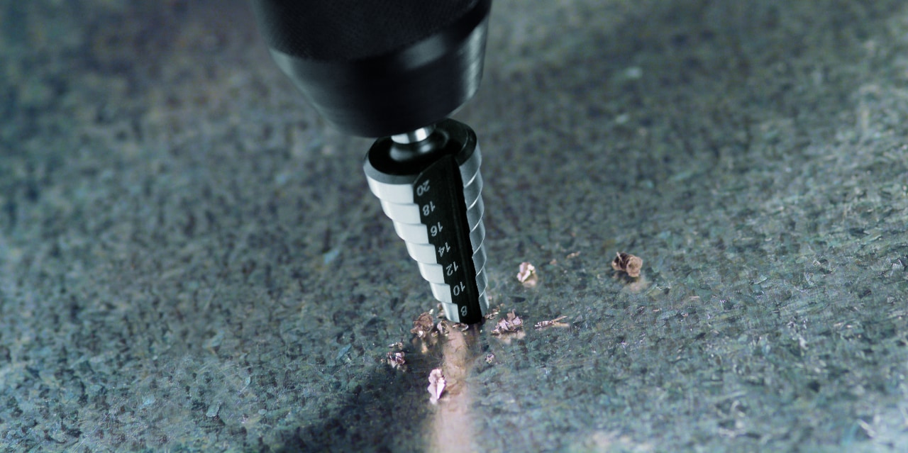 Stufenbohrer HSS beim Bohren auf einer Metallplatte