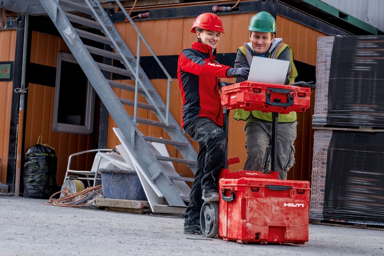 Abbildung zeigt eine Hilti Verkaufsberaterin in einem Gespräch mit einem Kunden, dabei steht das Laptop auf einer mittleren ProKit Werkzeugbox.