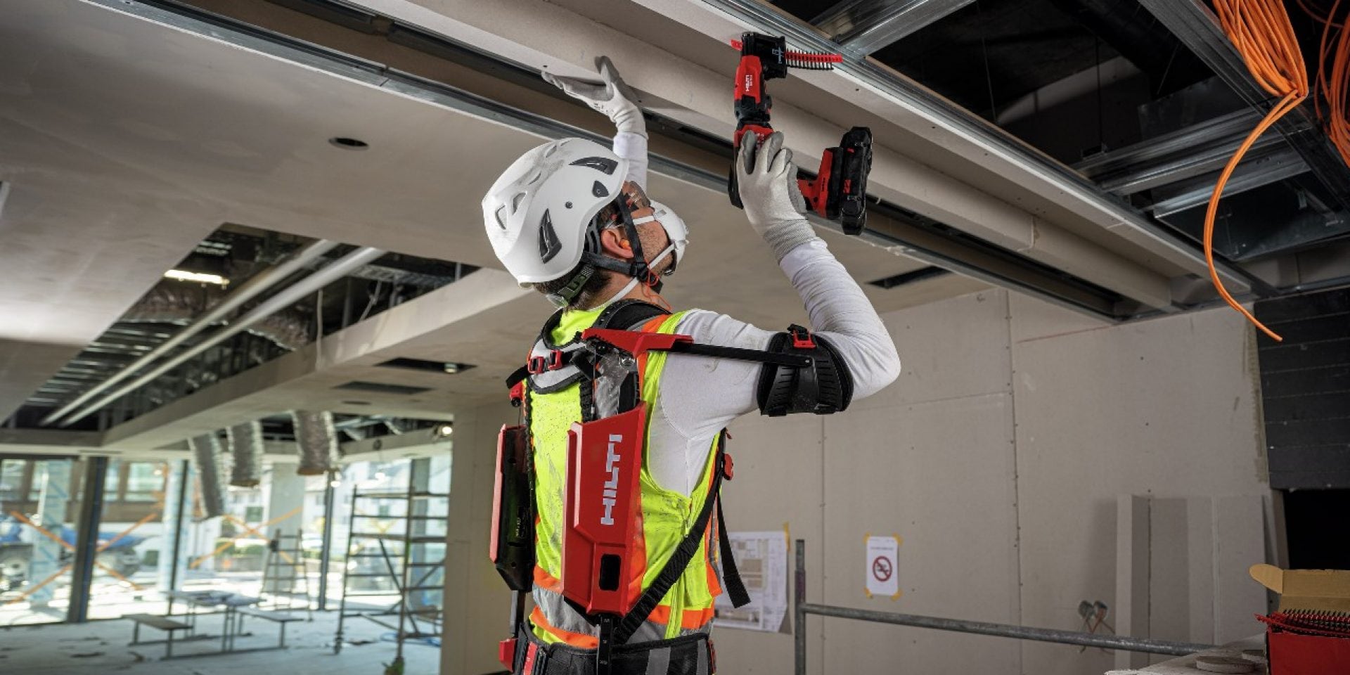 Eine Person mit Hilti Exo-Skelett arbeitet über Kopf. 